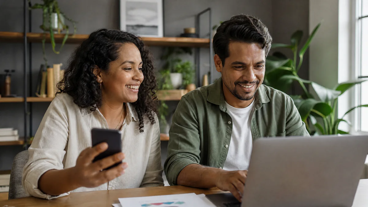 Casal de empreendedores conferindo as vendas no celular e no notebook