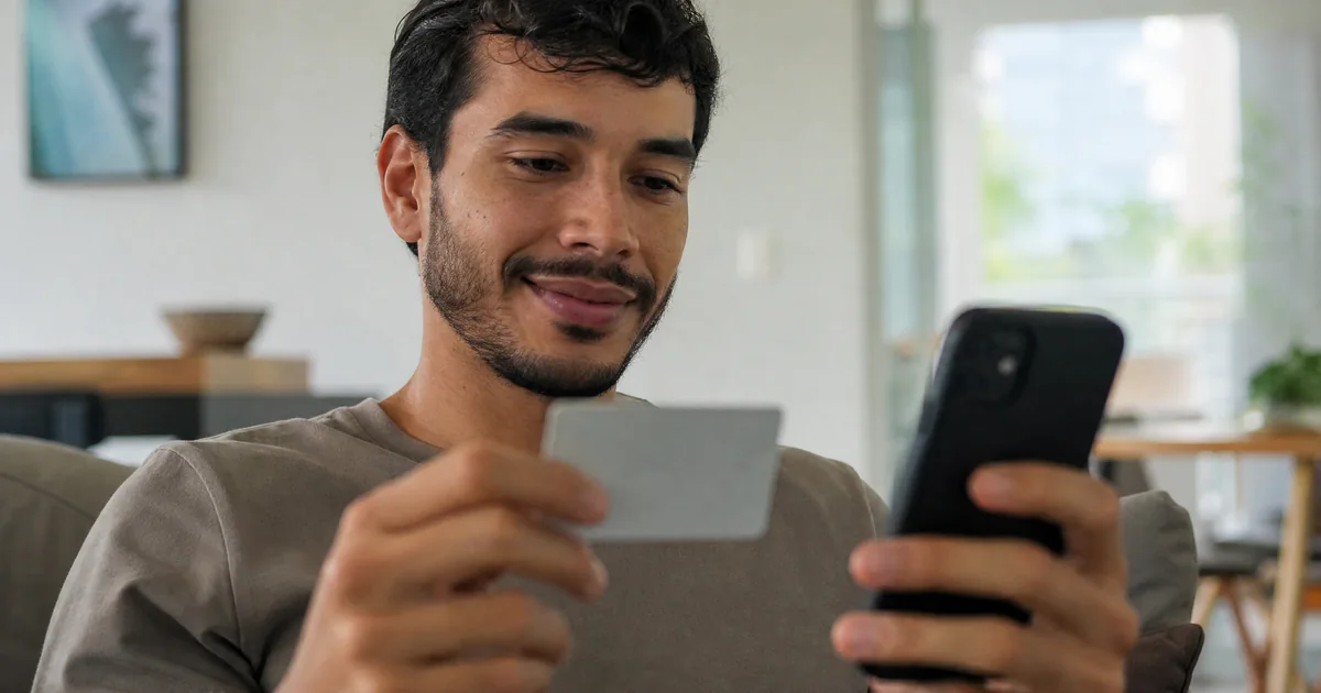 Cliente finalizando a compra no celular com o cartão na mão